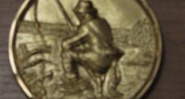 Złoty medal - strona z wędkarzem.